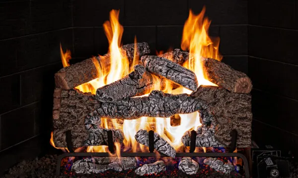 Fireplace with gas logs, flames burning, dark interior setting.