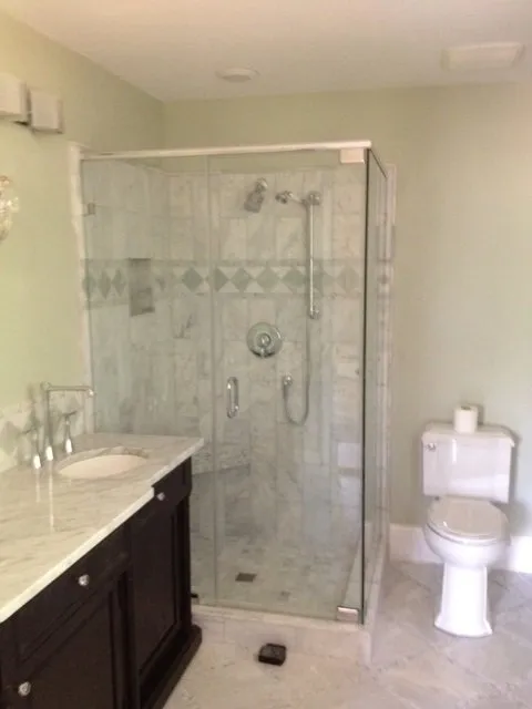 Bathroom with a glass shower, toilet, dark vanity, and pale green walls.