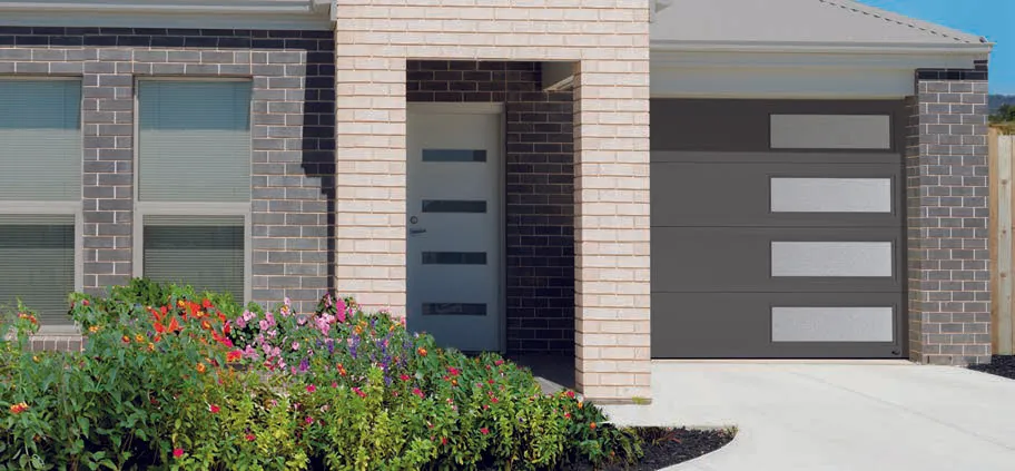 Garage door with frosted windows on an orange house with a brick driveway, palm trees.