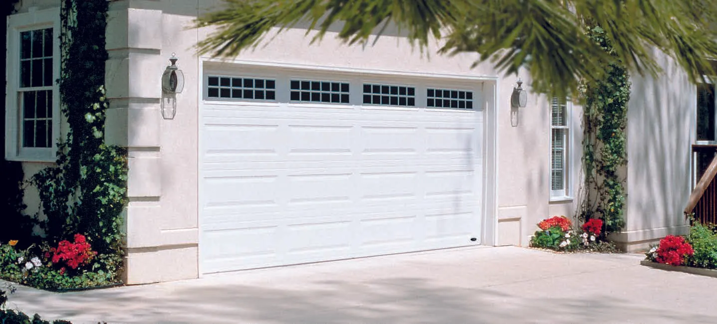 Black garage door with rectangular windows, tan trim, concrete driveway, white house exterior.