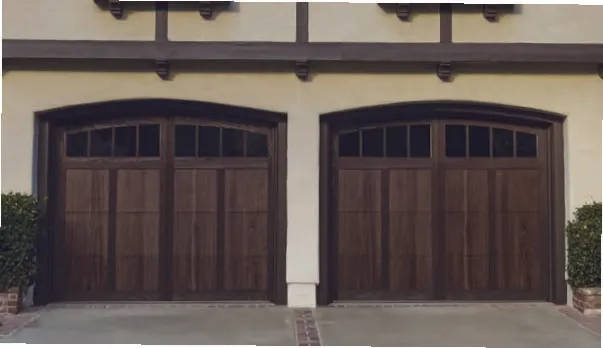 Two arched, dark wood-paneled garage doors with upper windows on a light-colored stucco building.