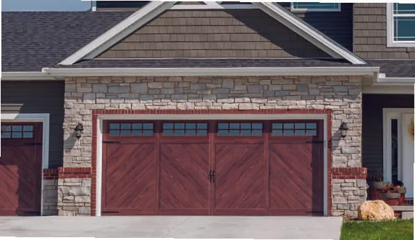 A two-car garage with deep red, diagonal-planked wooden doors and rectangular window insets, set in a stone-faced house.