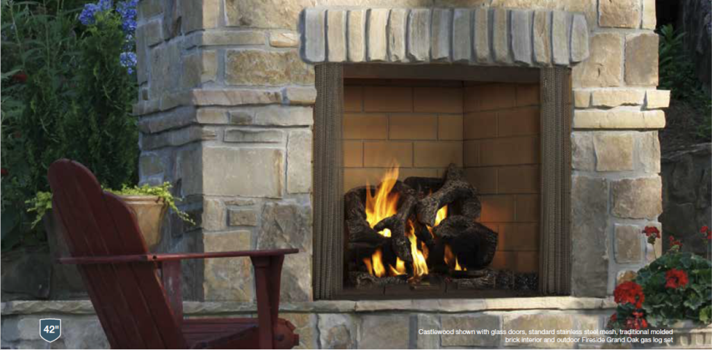 A stone fireplace with a burning fire, next to a red wooden chair, with greenery and flowers nearby.