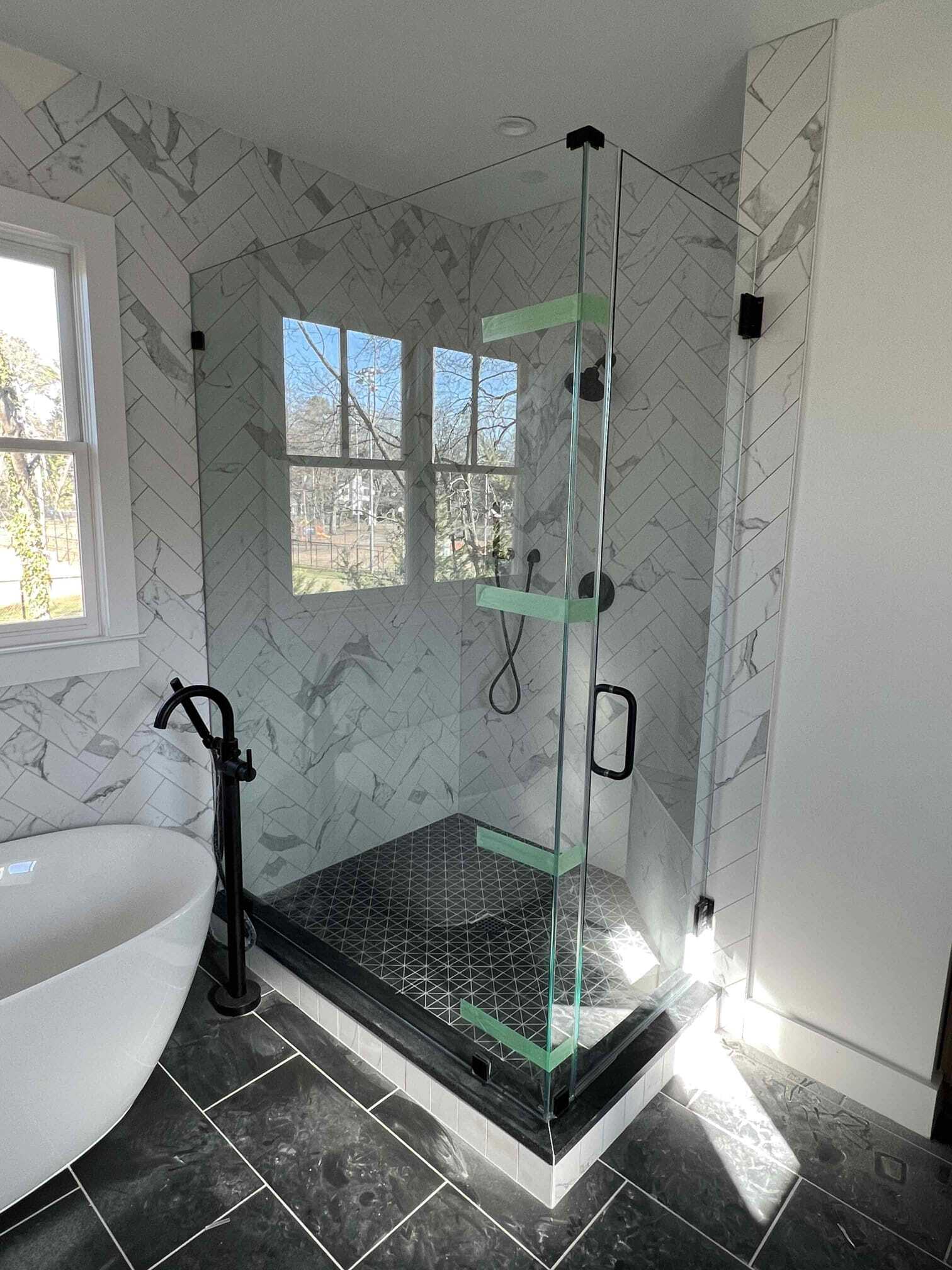 Glass shower enclosure with hexagonal design, green shelves, and tiled wall.