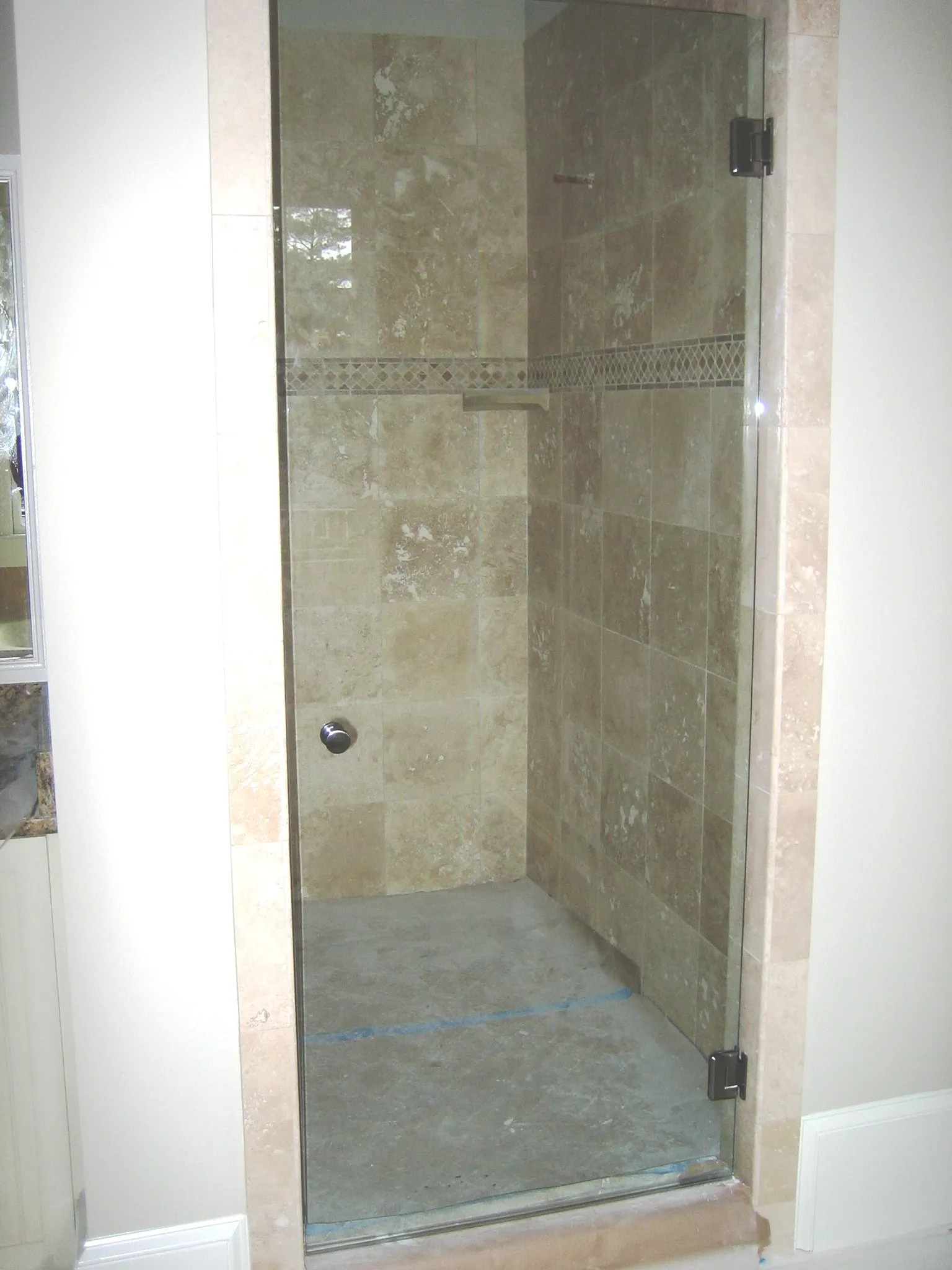 Shower stall with glass door and stone tile walls.