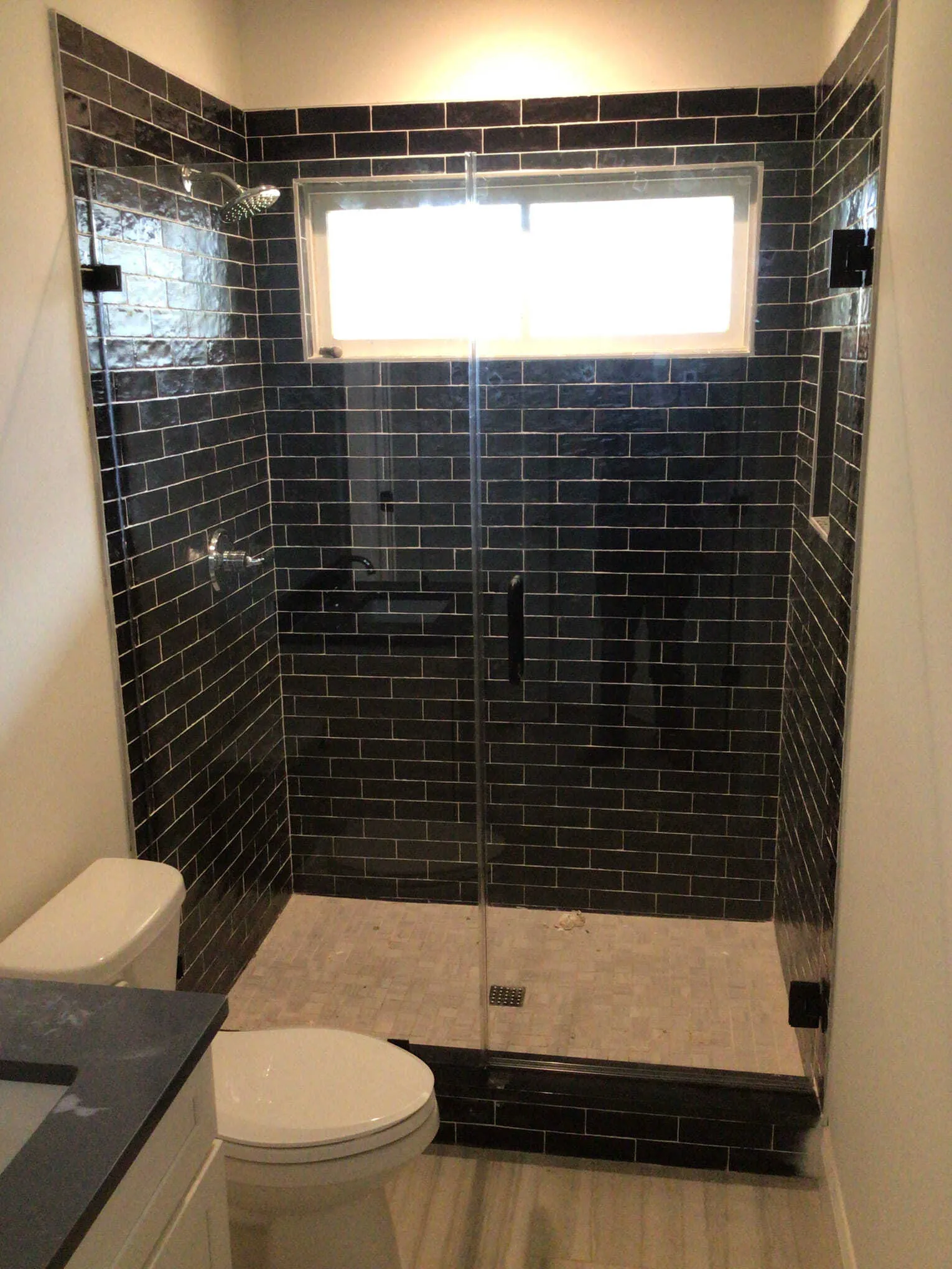 shower with glass doors and white marble tile.
