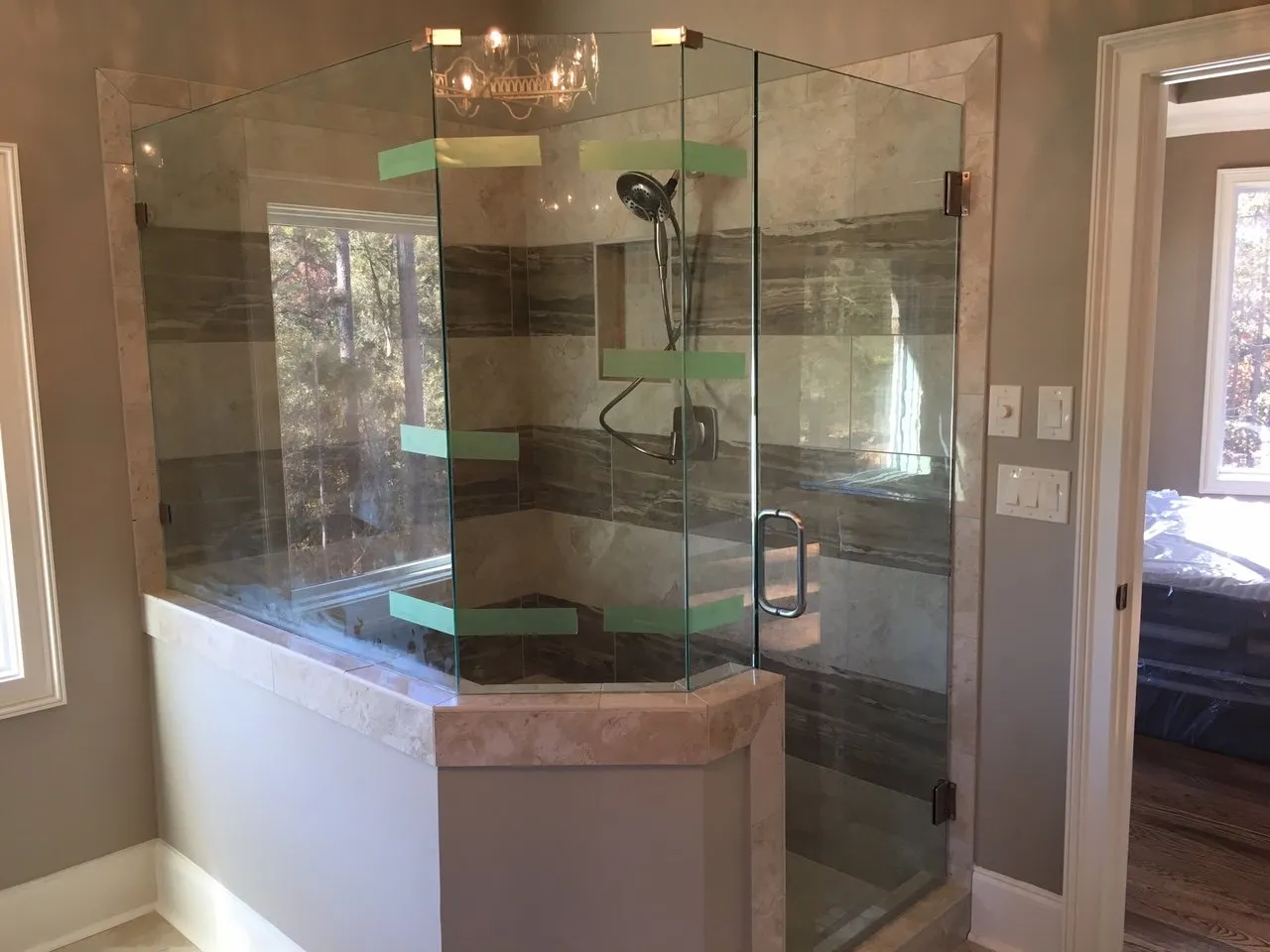 Glass shower enclosure with hexagonal design, green shelves, and tiled wall.
