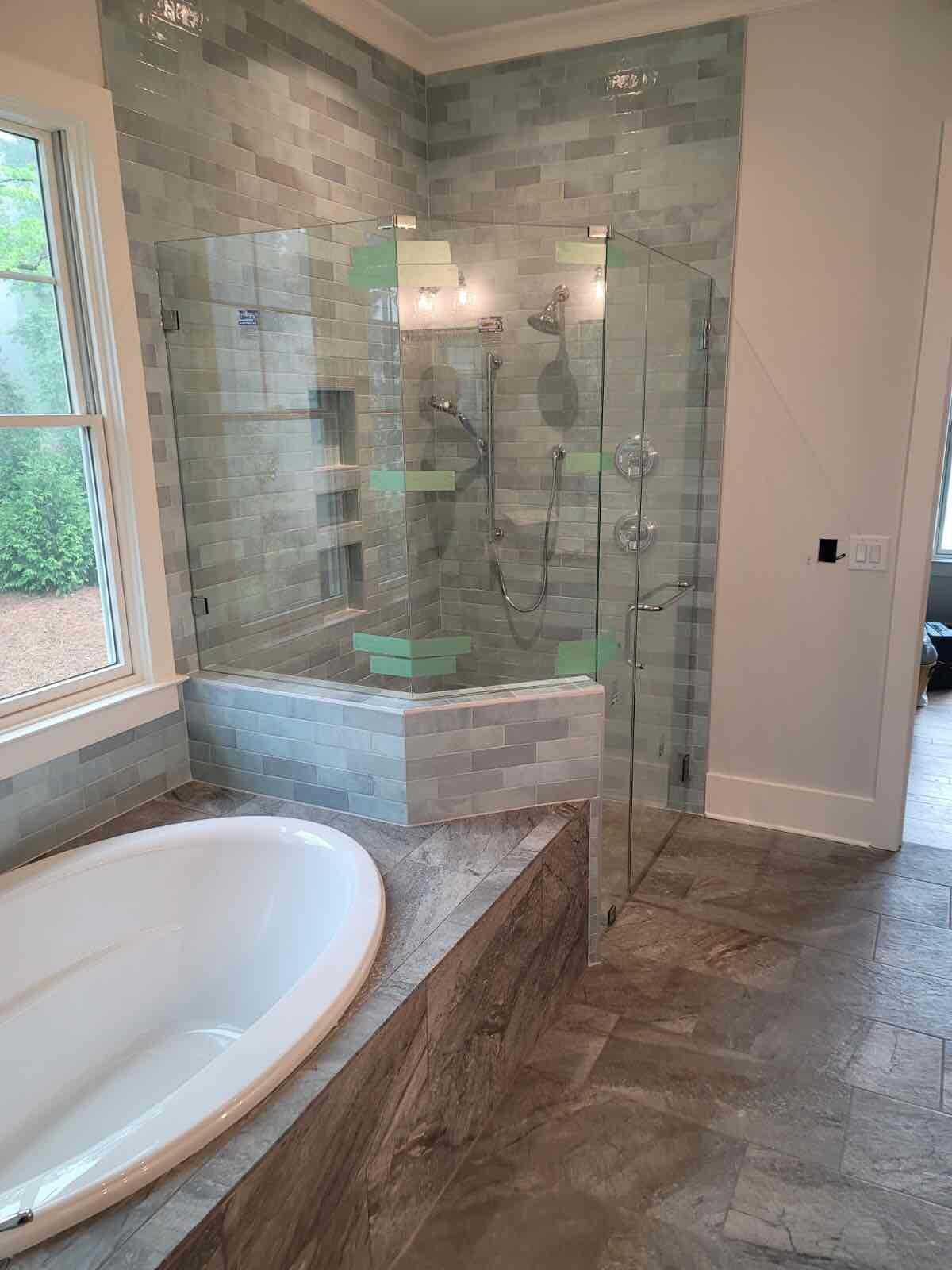 Bathroom with glass shower, soaking tub, and gray tile.