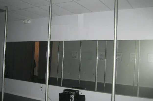 A fitness studio featuring several vertical exercise poles positioned in front of a large wall mirror.