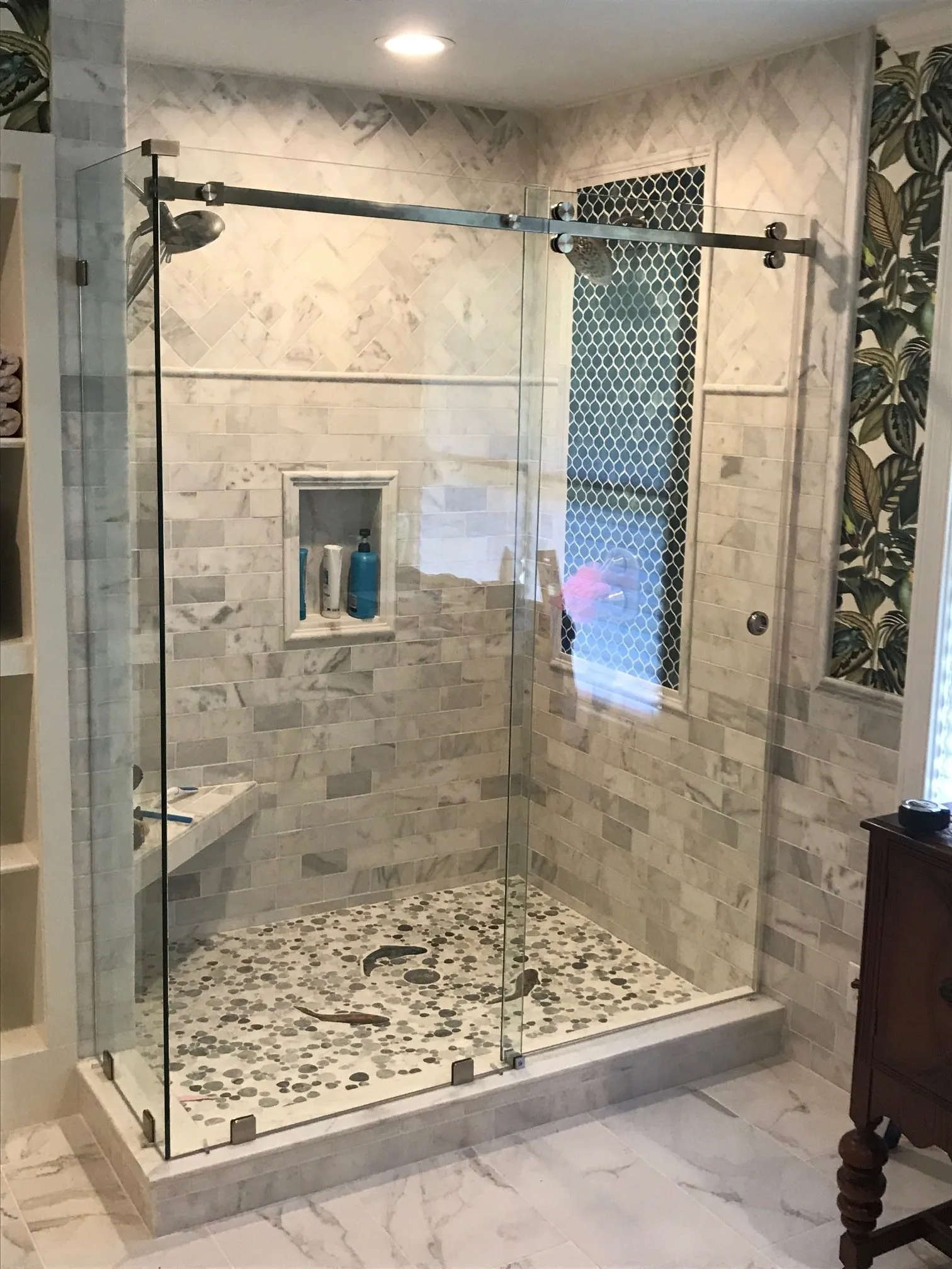 Modern glass-enclosed shower: hexagon tile floor, white walls, and built-in bench.
