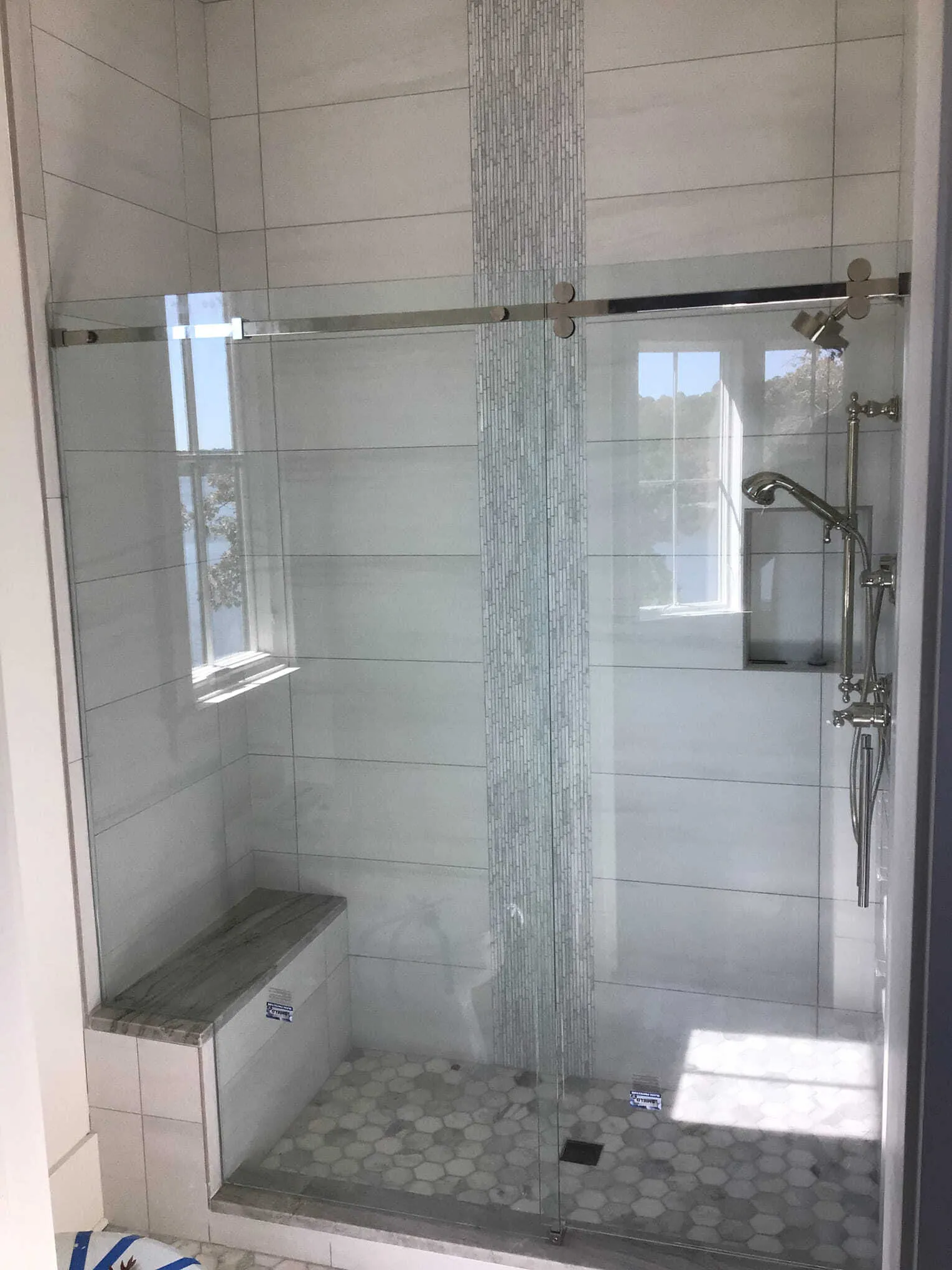 Modern bathroom with glass shower, marble tile, and a toilet.