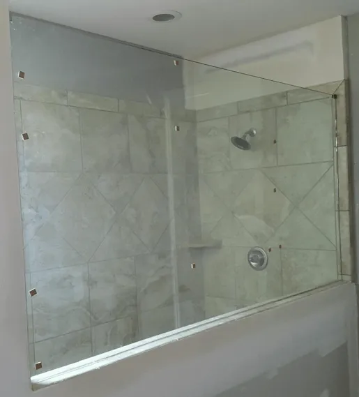 Glass shower enclosure with beige tiled walls.