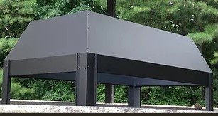 A black metal chimney cap with a slanted roof design mounted on a light-colored stone chimney top.
