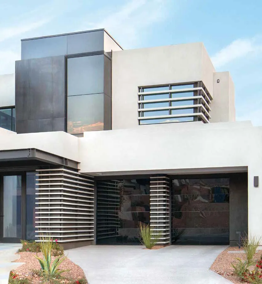 Modern white house with dark metal accents and slatted details. Blue sky background.