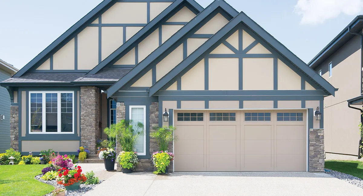 Tan and blue Tudor style house with garage and driveway.