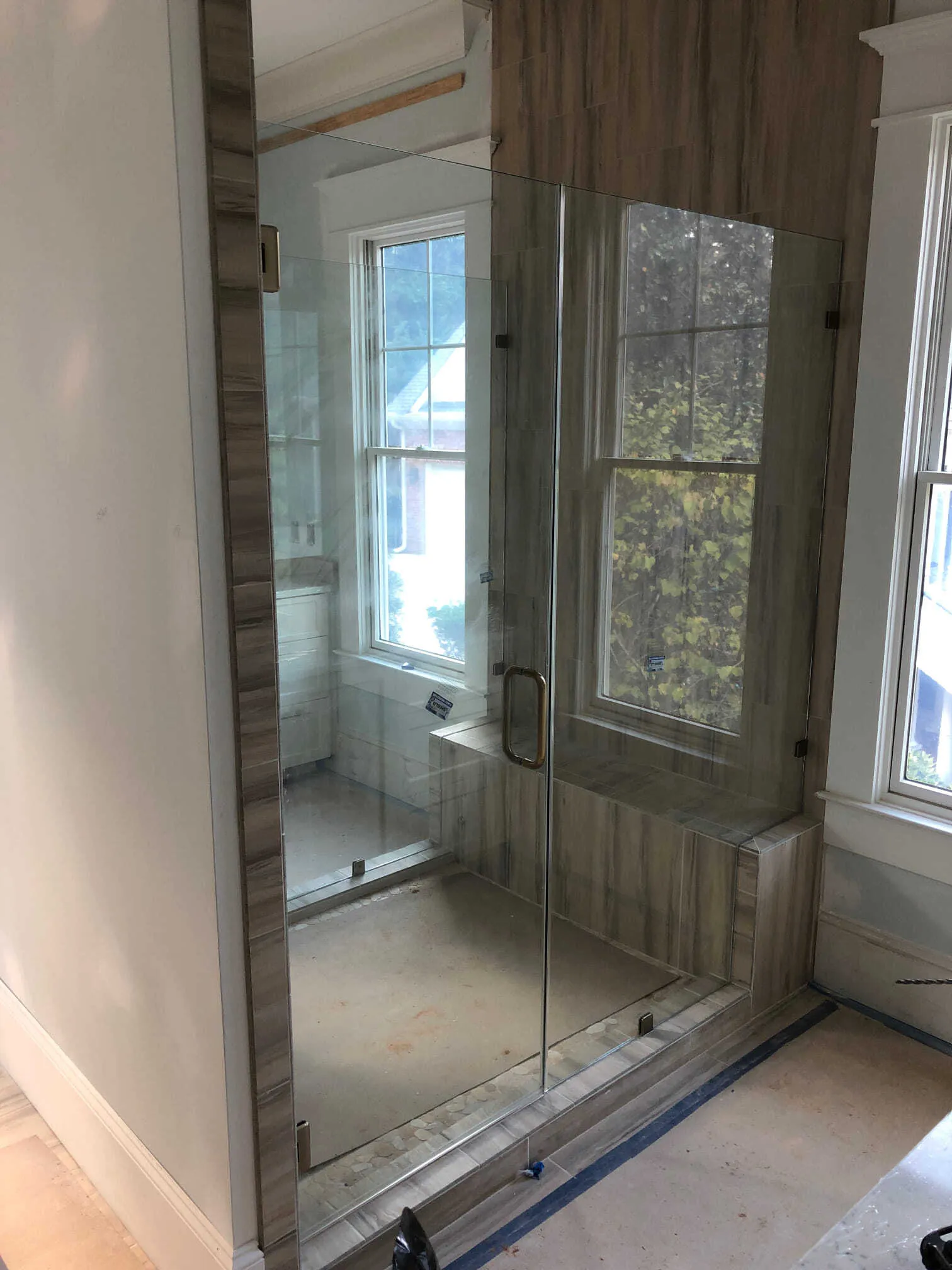 Glass-enclosed shower with a door, wood-look tiled walls, and a window