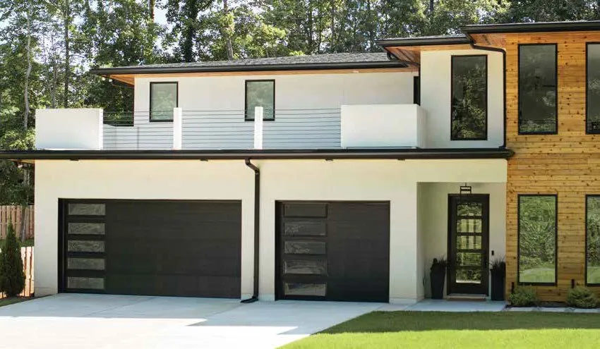 Modern house with black garage doors, white exterior, and a wood-paneled section.