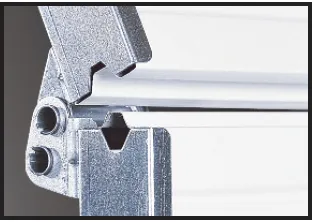 A close-up view of a metal hinge mechanism connecting two light-colored, grooved panels on a hinged…