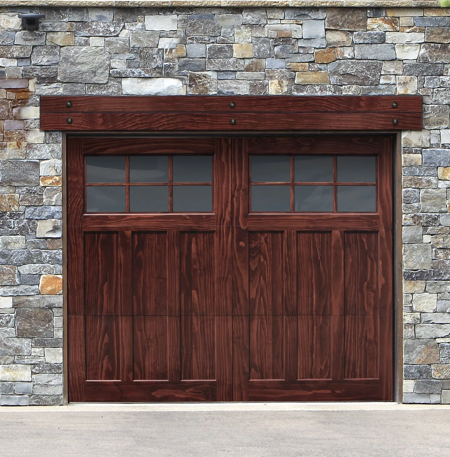 Wooden garage door with windows, set in a stone wall, topped with a dark wood beam.